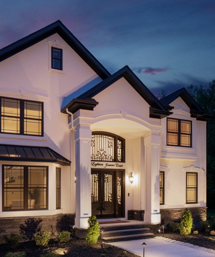 Exterior of home showing detailed door and black windows at evening